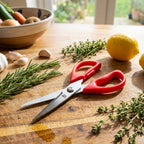 Red scissors on a wooden cutting board with herbs and lemons