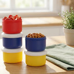 Colorful containers stacked on a wooden surface with a plant in the background