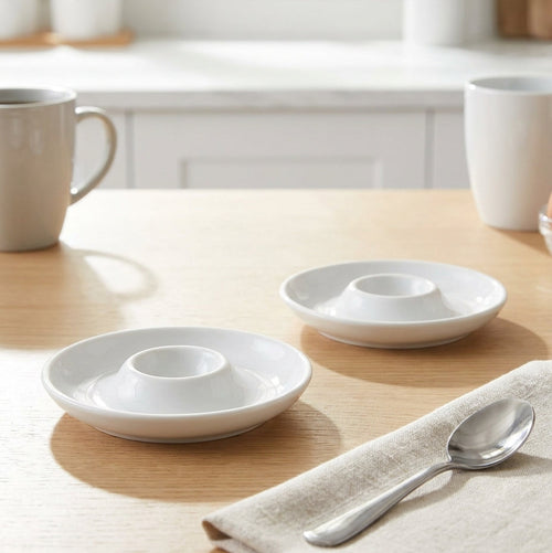 White ceramic bowls and a spoon on a wooden table with a neutral background