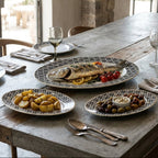 Dining table set with plates of food and wine glasses in a rustic setting.
