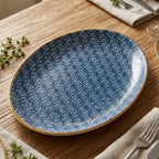 Blue speckled ceramic plate on a wooden table with silverware and napkins.