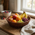 Fruit basket with apples, oranges, bananas, and grapes on a wooden countertop.