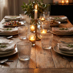 Dining table set for a meal with candles and greenery