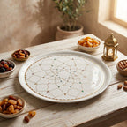 Decorative plate with intricate patterns on a wooden table with bowls of dried fruits.