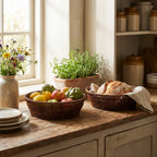 Kitchen counter with fruit bowl, bread basket, and potted plants near a window.