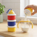 Person pouring milk from a container into a glass on a kitchen counter.