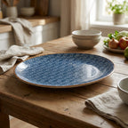 Blue speckled ceramic plate on a wooden table with bowls and apples in the background.